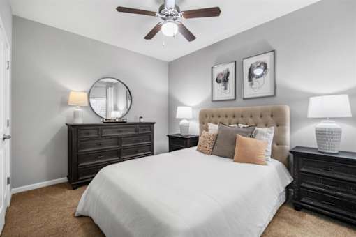 A bedroom with a large bed, a dresser, and a ceiling fan.