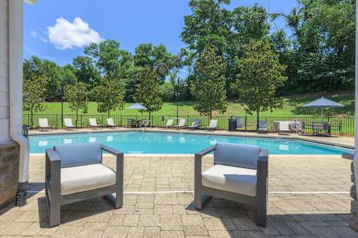 Two chairs are placed on a patio by a pool.