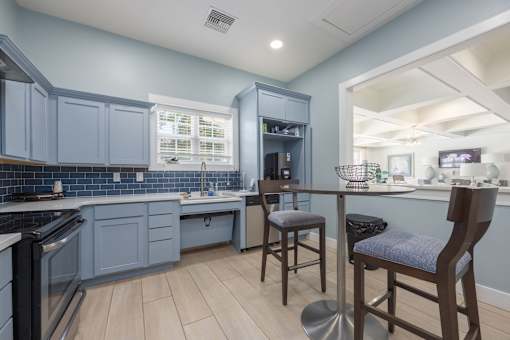 A kitchen with a blue cabinetry and wooden flooring.