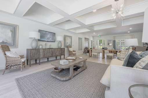A spacious living room with a large grey rug and a white sofa.