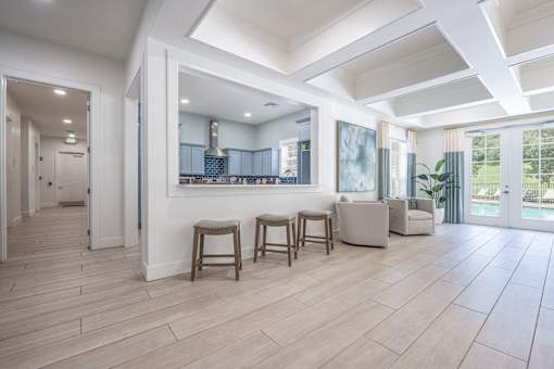 A spacious living room with a kitchen in the background and a dining table with chairs in the foreground.