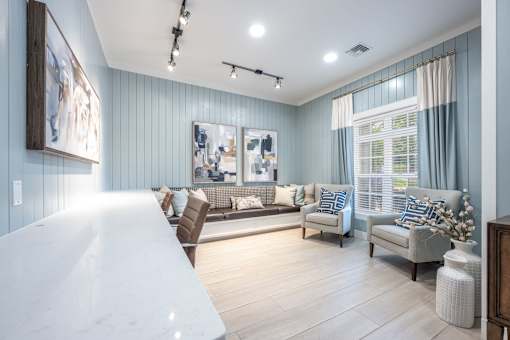 A living room with a white couch and a painting on the wall.