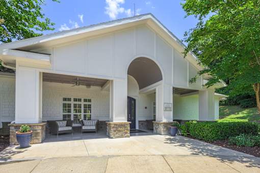 A white house with a covered entrance and a stone pillar.