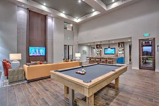 A billiard table is in the middle of a room with a television and a couch.