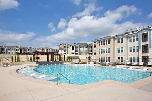 A large swimming pool in front of apartment buildings.