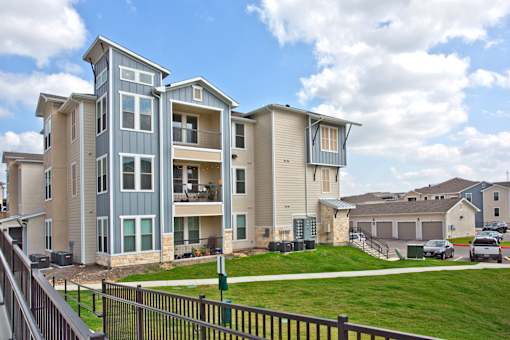 A large apartment complex with multiple buildings and a green lawn in front.