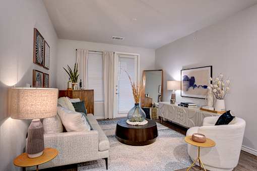 A living room with a white couch, a brown coffee table, and a lamp on a side table.
