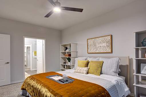 A bedroom with a bed, a ceiling fan, and a bookshelf.