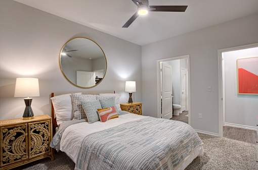 A bedroom with a bed, nightstand, and a painting on the wall.