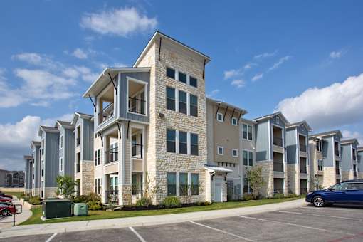 A row of modern apartment buildings with a blue car parked in front.