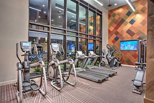 A gym with treadmills, exercise bikes, and a television.