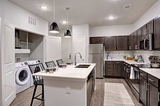 A modern kitchen with a white island and dark brown cabinets.