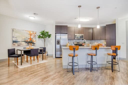 a kitchen with a bar and a dining area with chairs at The Mark, San Antonio, 78230
