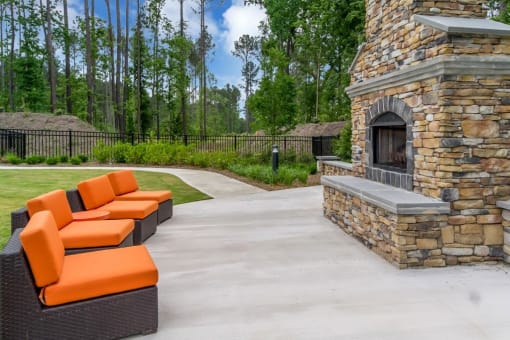 a concrete patio with orange couches and a stone fireplace at Sterling Creek, Richmond Hill