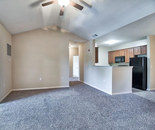 an empty living room with a kitchen and a ceiling fan at Mill Creek Run, Georgia