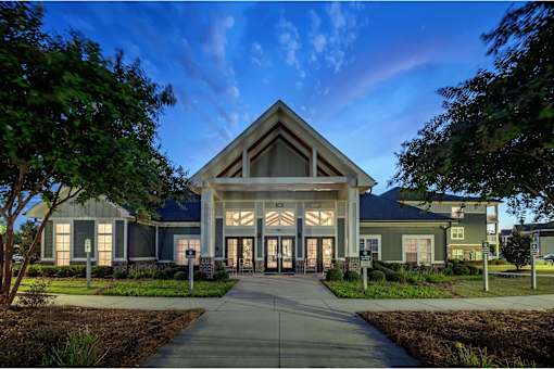 A modern building with a large front entrance and a pathway leading to it at Waterleaf at Neely Ferry Apartments, Simpsonville, SC