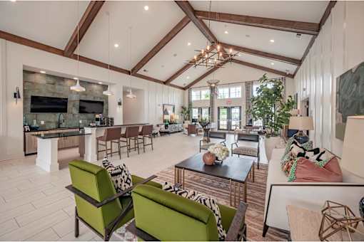 A modern living room with a stone fireplace and a large green sofa at Waterleaf at Neely Ferry Apartments, Simpsonville, South Carolina