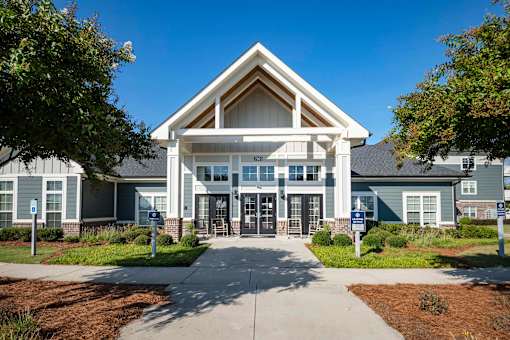 A large building with a triangular roof and a covered entrance at Waterleaf at Neely Ferry Apartments, Simpsonville, 29680