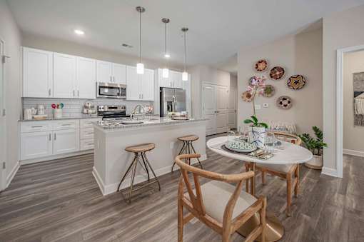 A kitchen with a table and chairs in the middle of the room at Waterleaf at Neely Ferry Apartments, Simpsonville, South Carolina