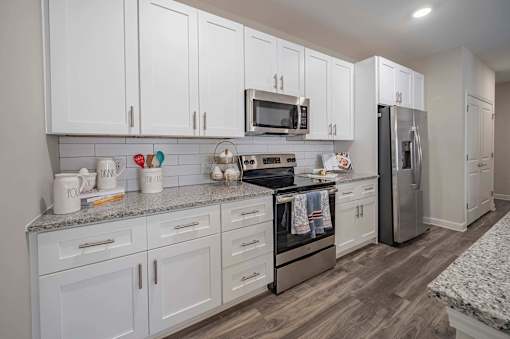 A kitchen with white cabinets with a granite countertop at Waterleaf at Neely Ferry Apartments, South Carolina 29680