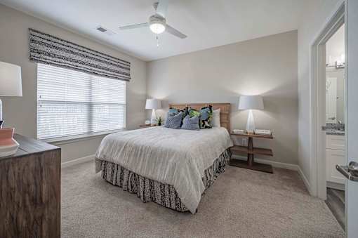 A bedroom with a bed, two lamps, and a ceiling fan at Waterleaf at Neely Ferry Apartments, Simpsonville
