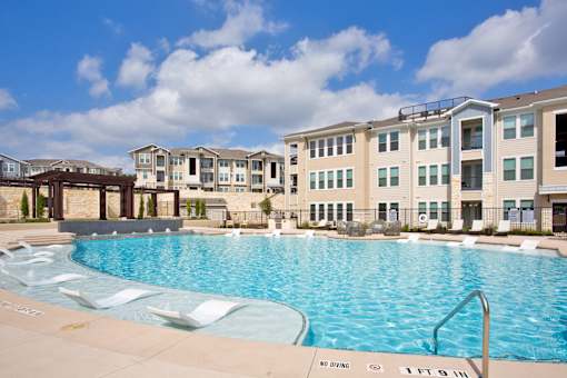 A large swimming pool in front of apartment buildings with a "No Diving" sign.