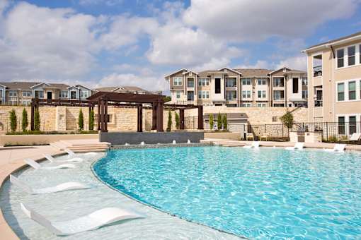 A large swimming pool in front of apartment buildings.