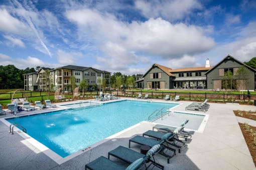 a swimming pool with chairs around it in front of a building at Bellary Flats Apartments, Summerville , 29486