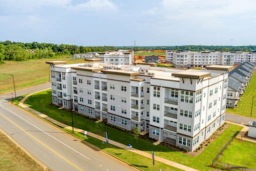 A large white apartment building with a green lawn in front.