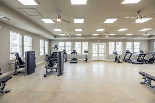 A spacious gym with various exercise equipment and a ceiling fan.