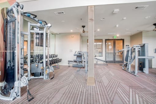a gym with weights and cardio machines and a glass door  at Edge and Stone, San Antonio