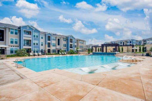 a large swimming pool with an apartment building in the background  at Edge and Stone, Texas