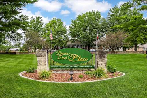 A sign for Brawn Deer Place Retirement Living and Memory Care Community is displayed in a grassy area.