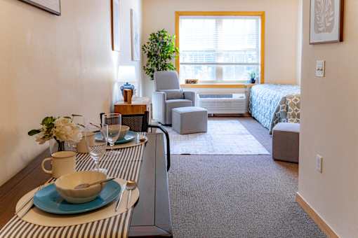 a living room with a dining table and a bedroom with a bed