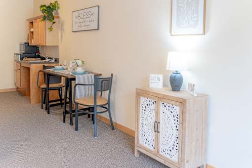 a dining area with a table and chairs and a cabinet with a lamp