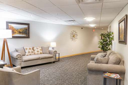 a living room with couches and chairs and a painting on the wall