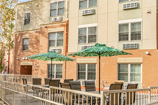 a patio with chairs and umbrellas in front of a building