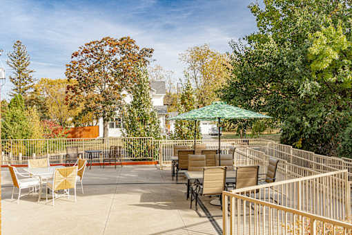 an outdoor patio with tables and chairs and a green umbrella