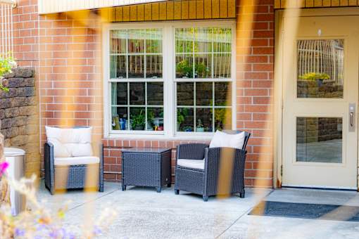 the porch of a home with two chairs and a door