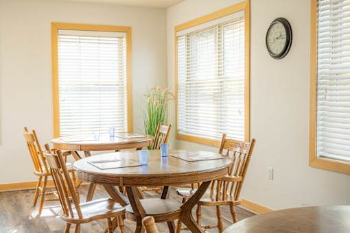 a dining room with two tables and chairs and two windows