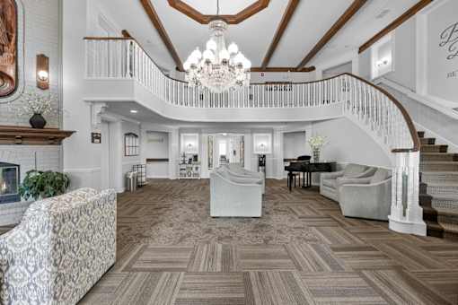 A large, open living room with a staircase and a fireplace.