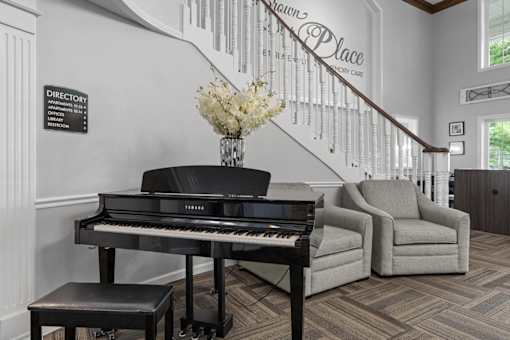 A grand piano sits in front of a wall with a directory sign.