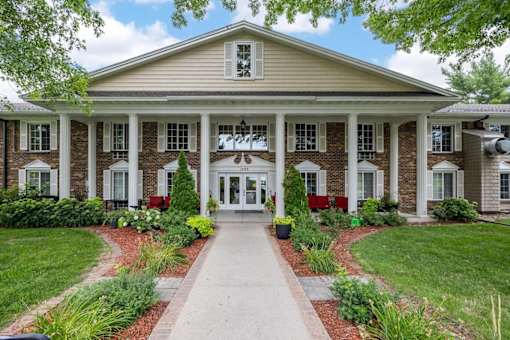 A building with a white door and windows surrounded by greenery.