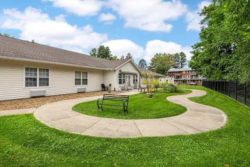 A house with a green lawn and a bench in front of it.