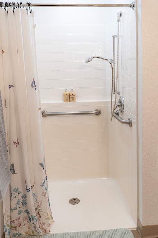 A white shower stall with a shower curtain and a shower head.