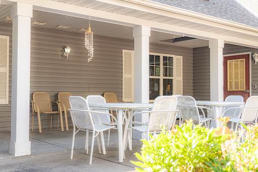A white table and chairs are set up on a porch.