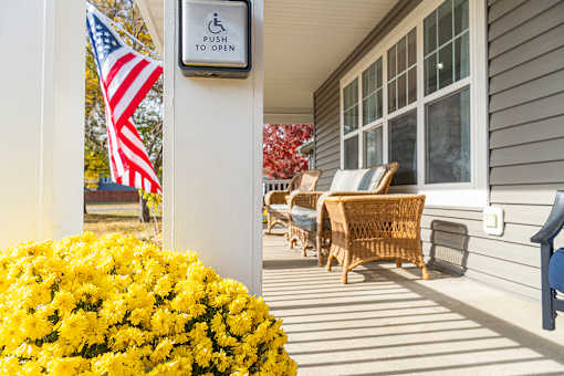 A sign on a pole that says "push to open" is next to a yellow flower bed.