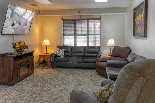 A living room with a grey couch and a wooden entertainment center.