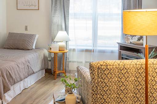 A bedroom with a bed, a chair, and a lamp.