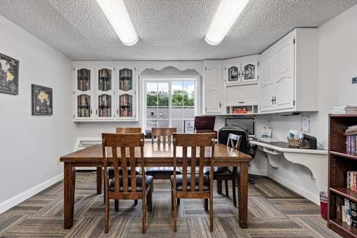 A kitchen with a table and chairs in front of a window.